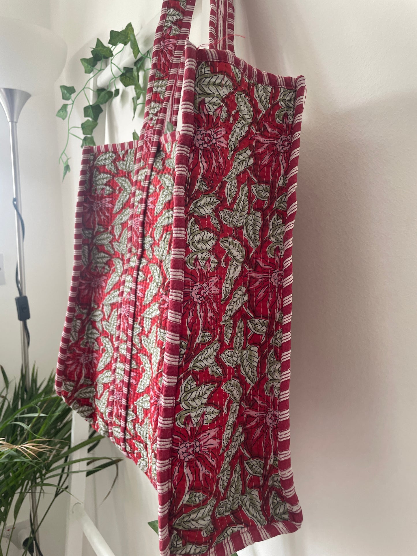 Red and green patterned fabric draped over a white surface with plants in the background