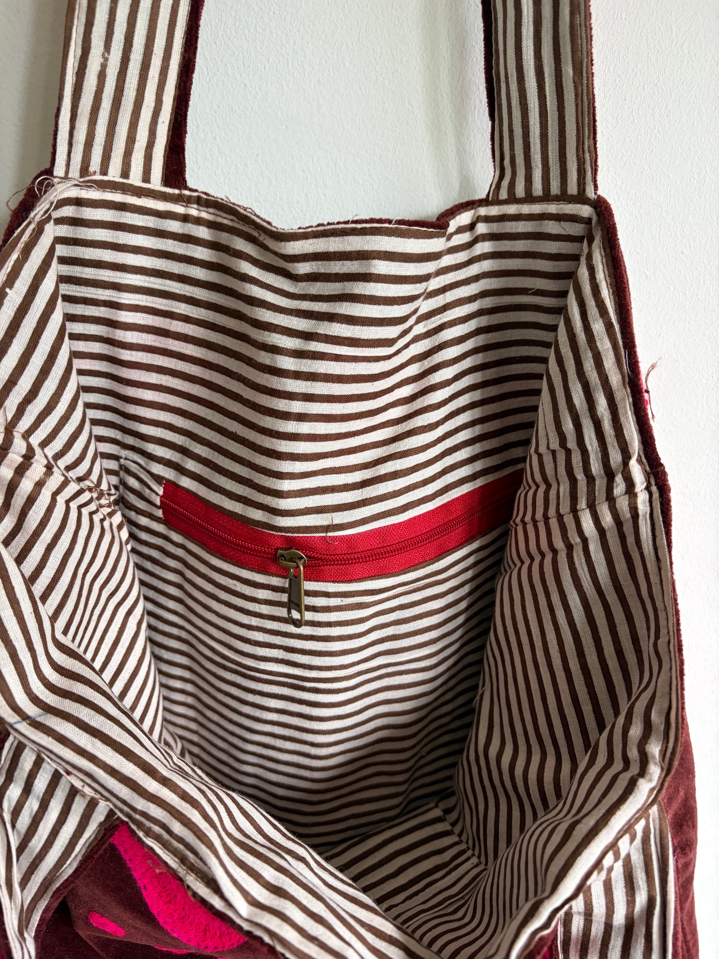 Brown tote bag with pink 'PEACE' text and heart designs on a plain background
