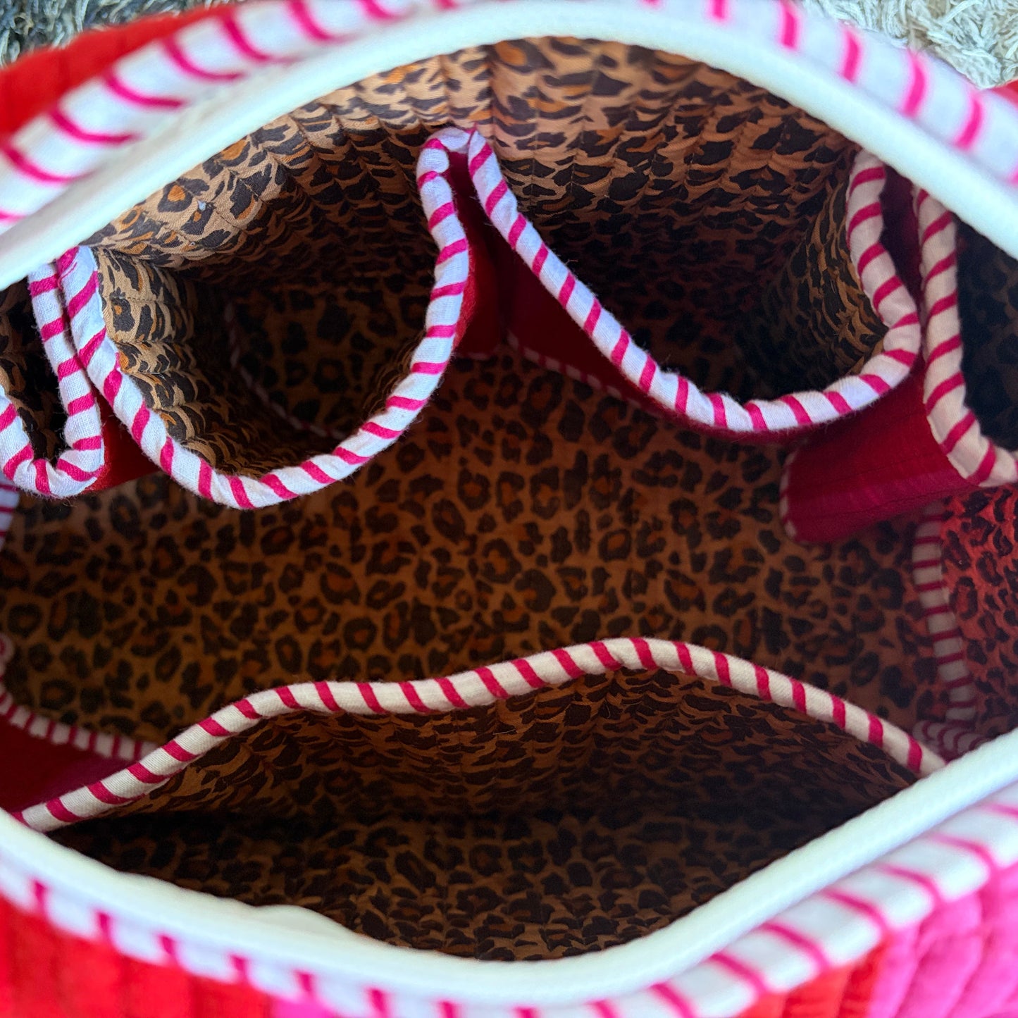 Quilted make up bag with stripes in shades of red and pink.