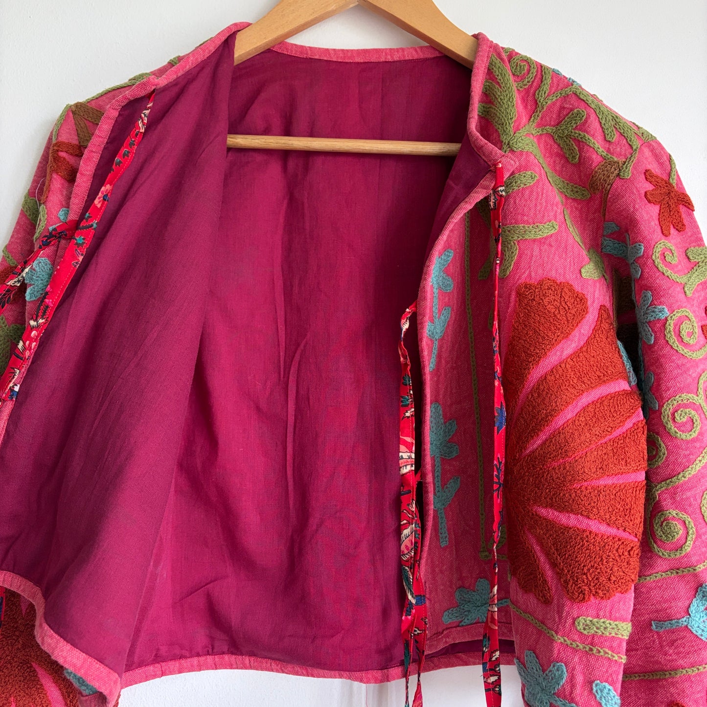 A cropped long-sleeve jacket with a vibrant pink and red floral pattern.