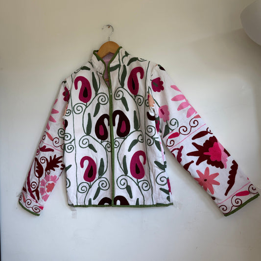 White quilted jacket with pink, green, and black embroidered paisley and floral patterns.