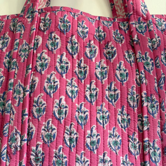 Pink quilt with floral pattern on a white background