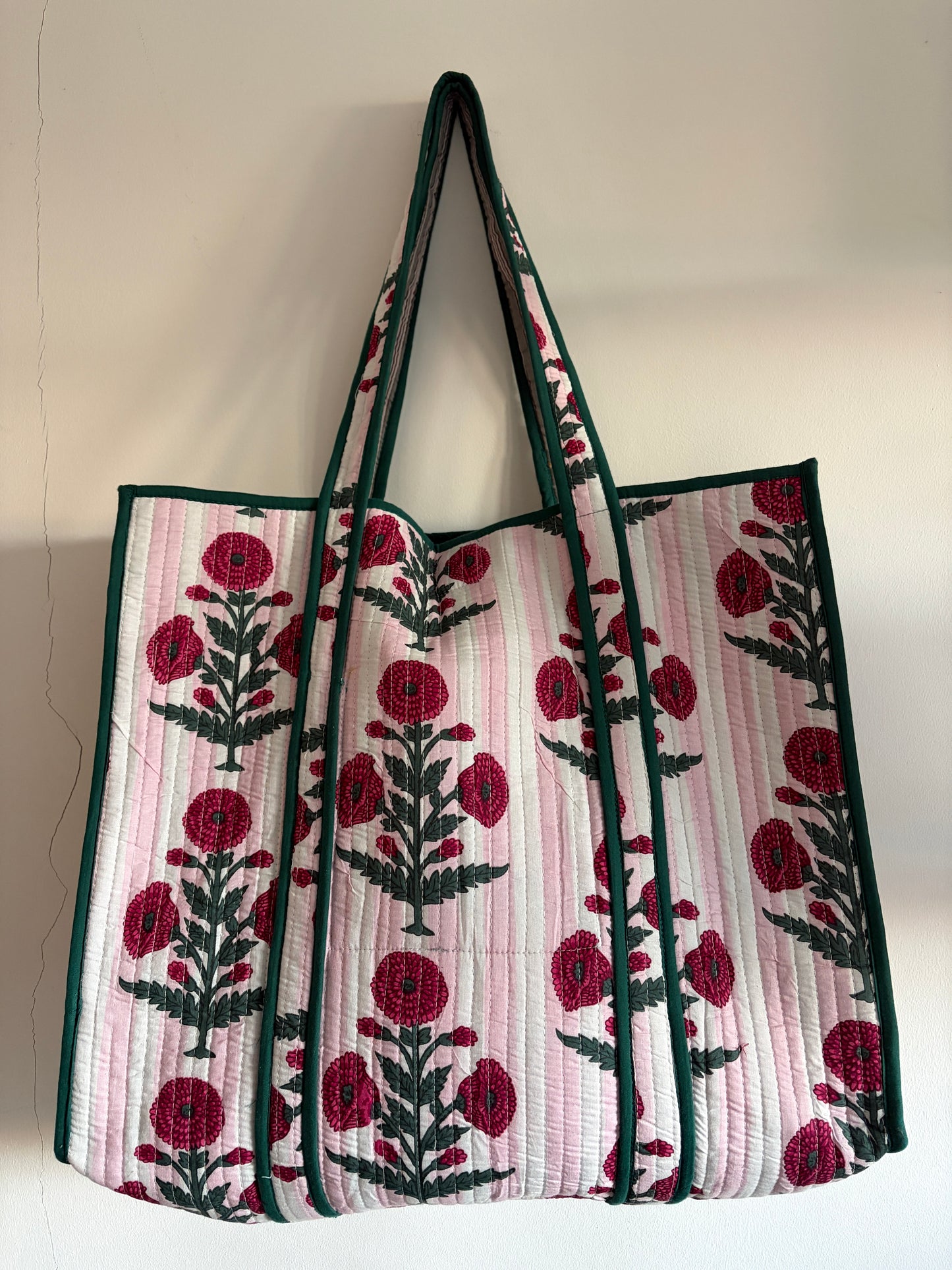 Floral patterned tote bag with red flowers and green leaves on a light background