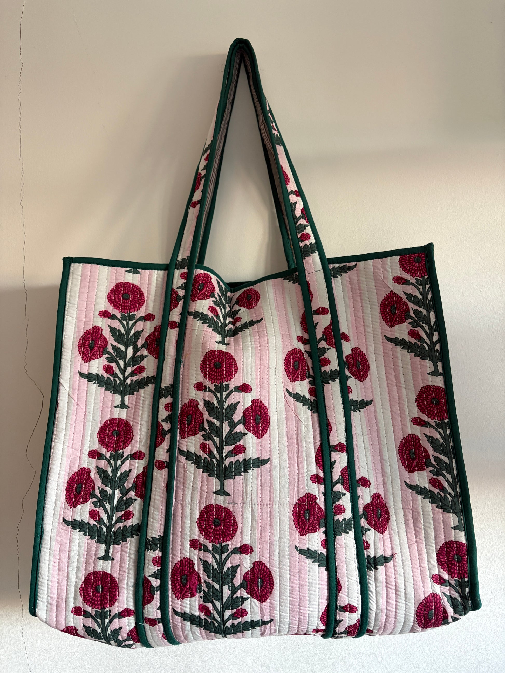 Floral patterned tote bag with red flowers and green leaves on a light background