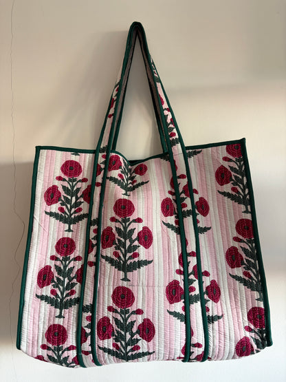 Floral patterned tote bag with red flowers and green leaves on a light background