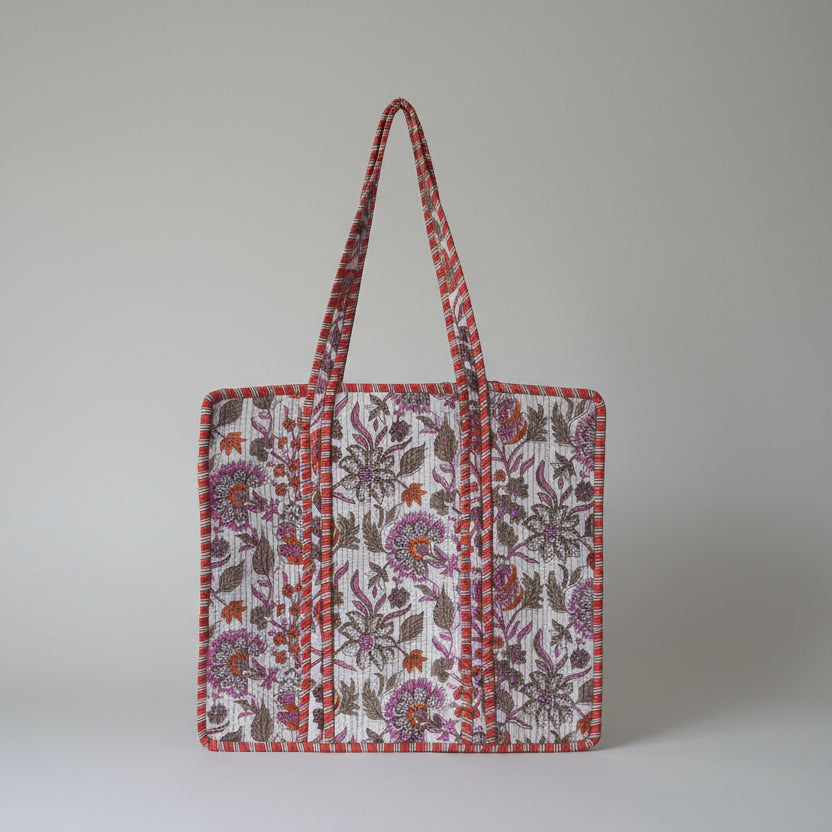 Floral patterned bag on a white surface with green plants