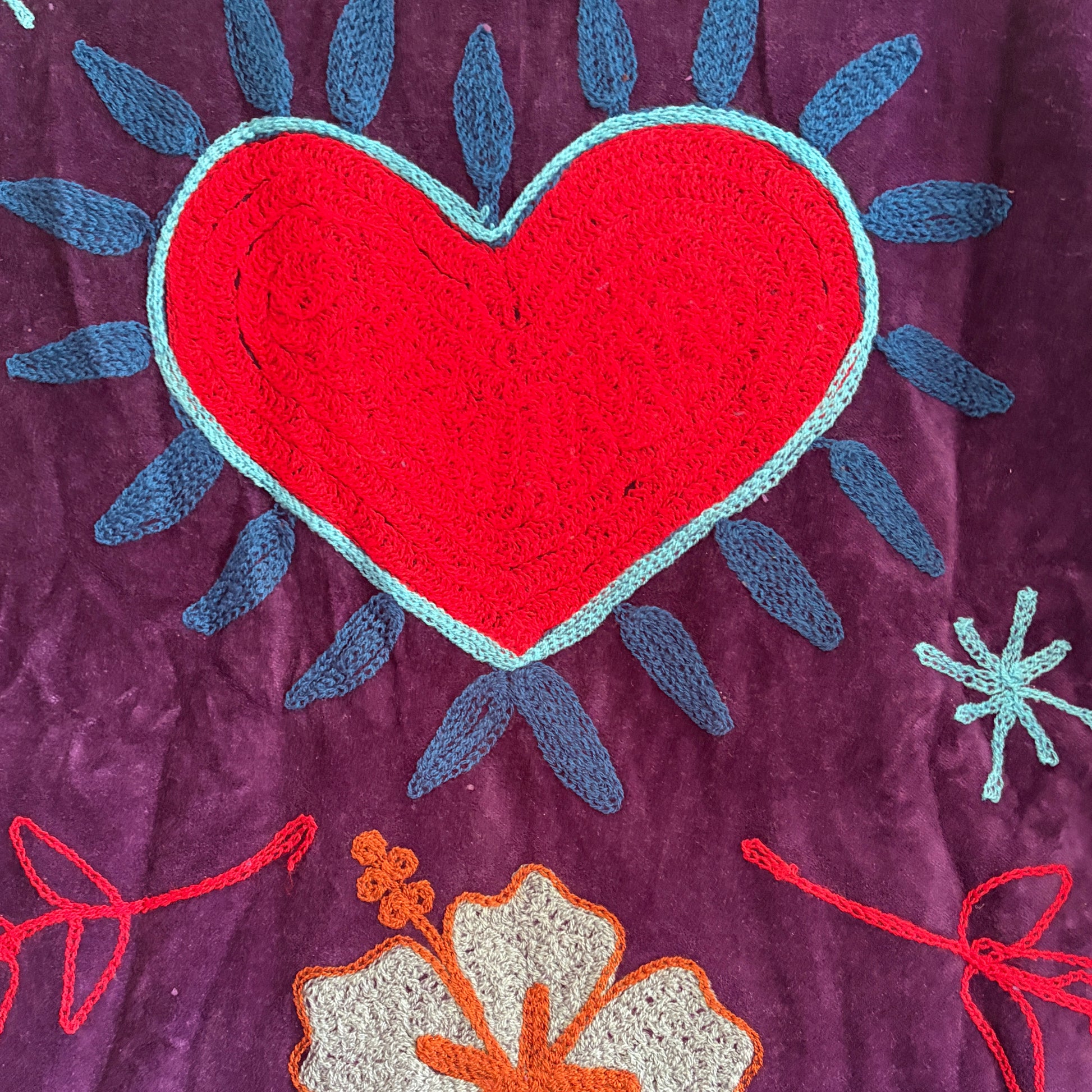 Embroidered fabric with colorful floral patterns on a purple background