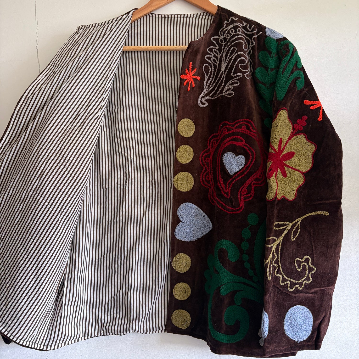Embroidered fabric with colorful patterns on a hanger against a white background