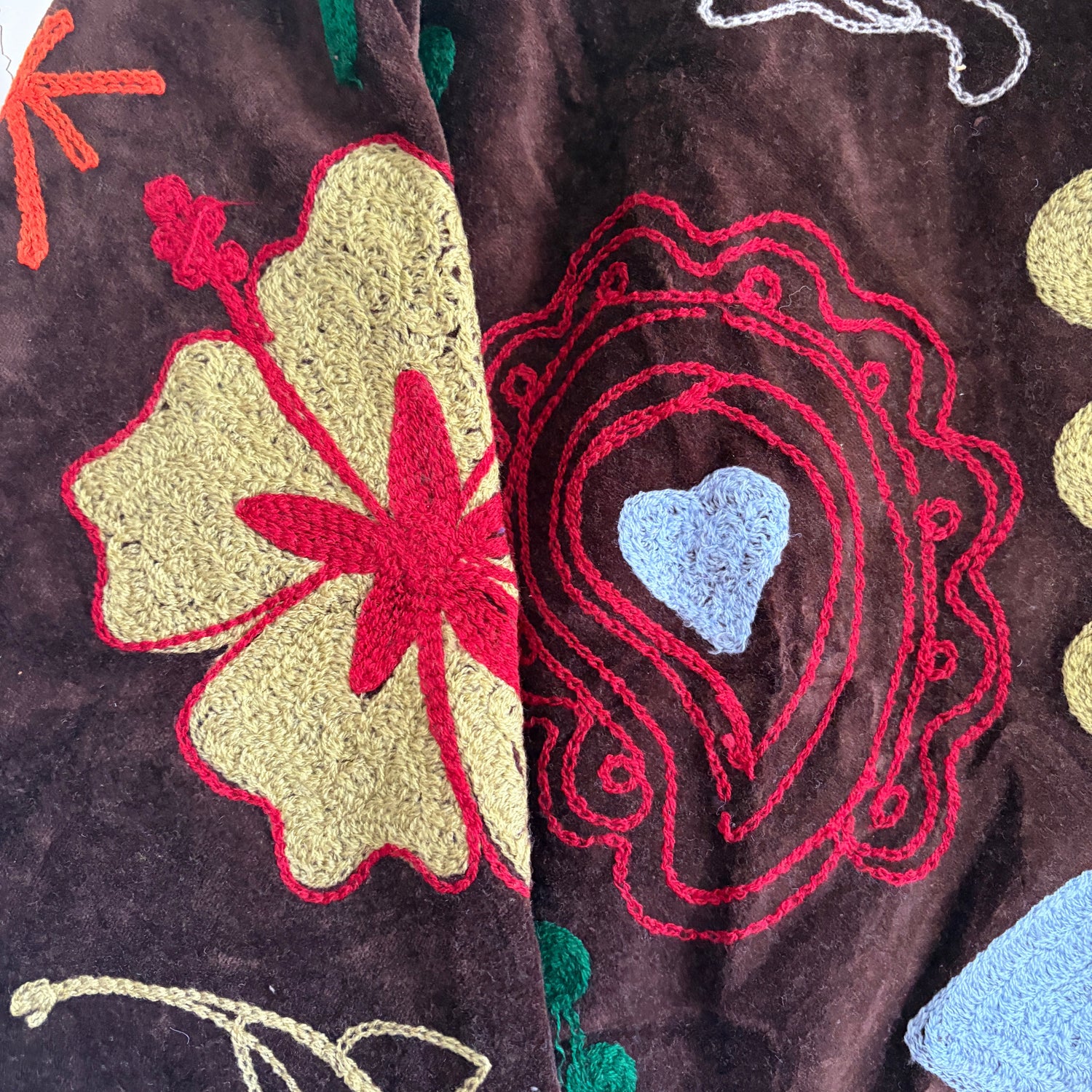 Embroidered fabric with colorful floral and leaf patterns on a dark background