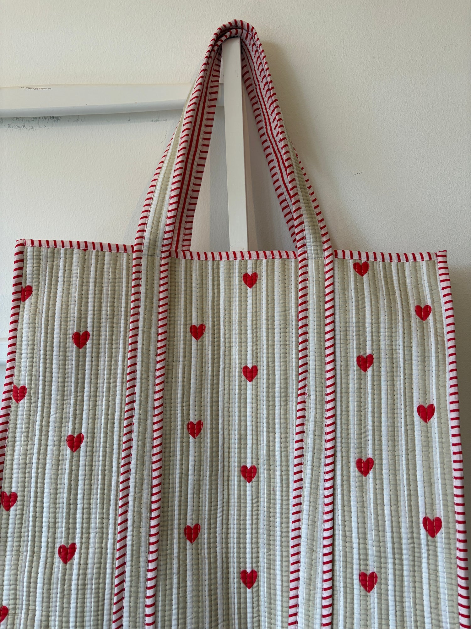 Tote bag with red heart patterns and striped design on a white background