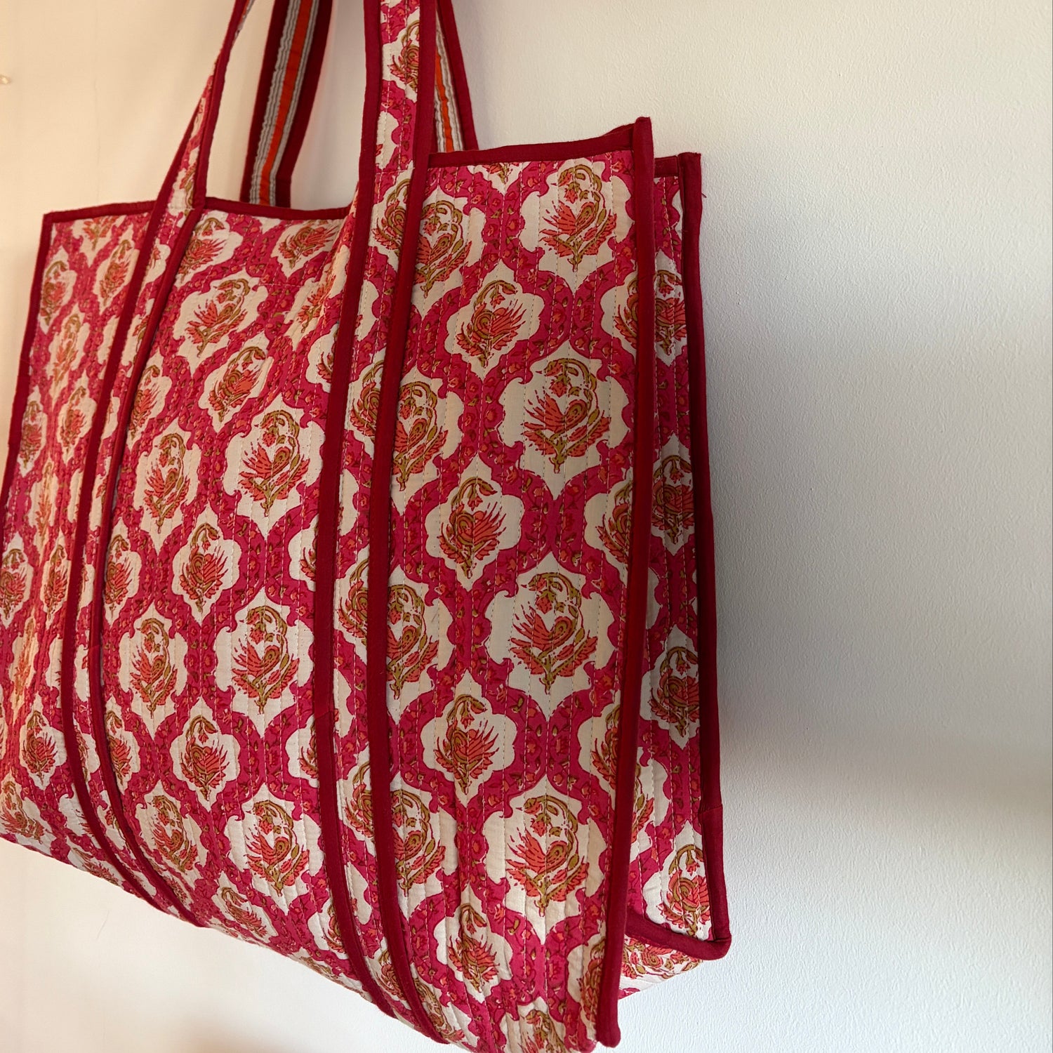 Red and white patterned fabric  tote bag on a beige surface