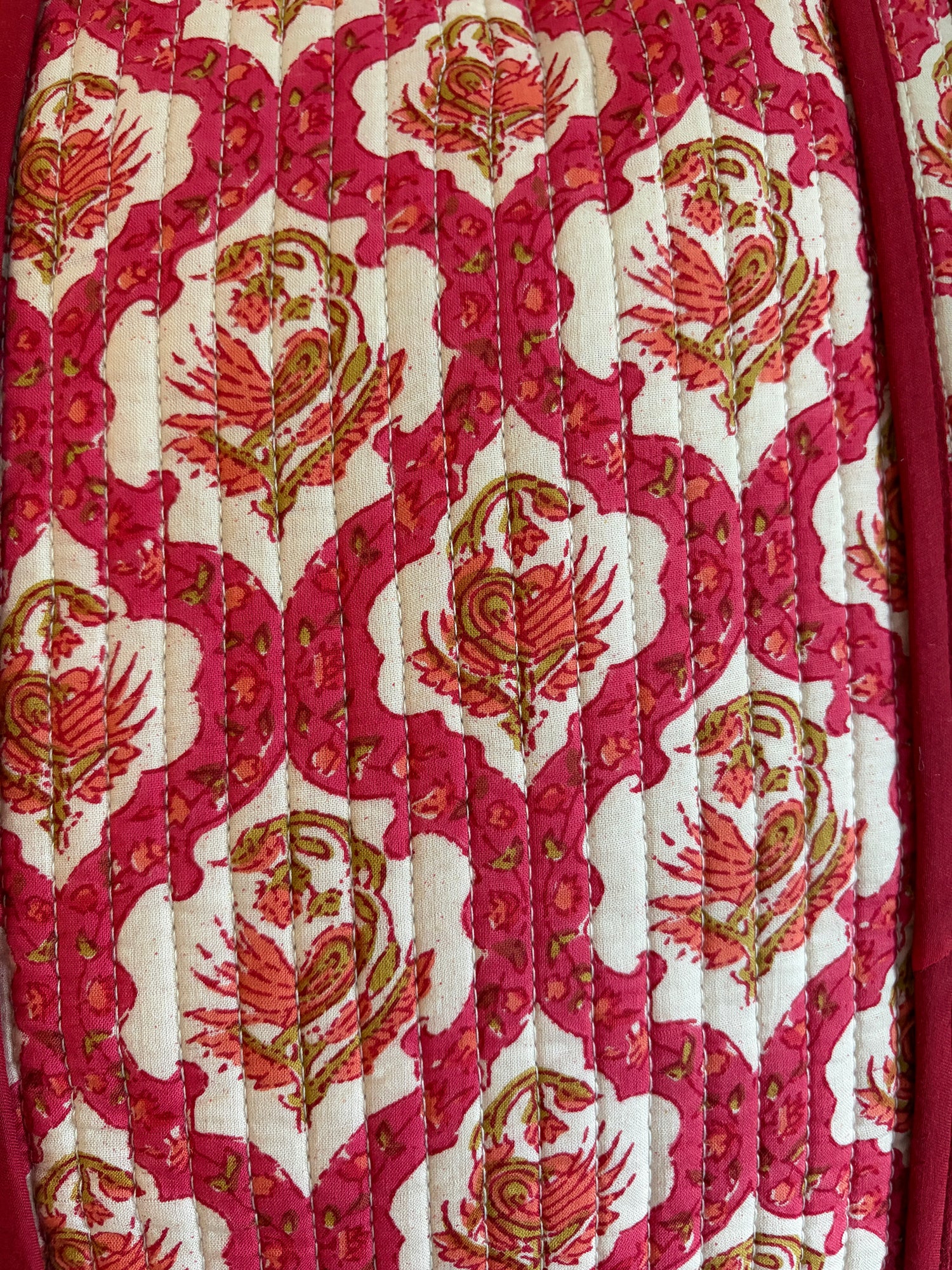 Quilt with red and gold floral pattern bag on a white background