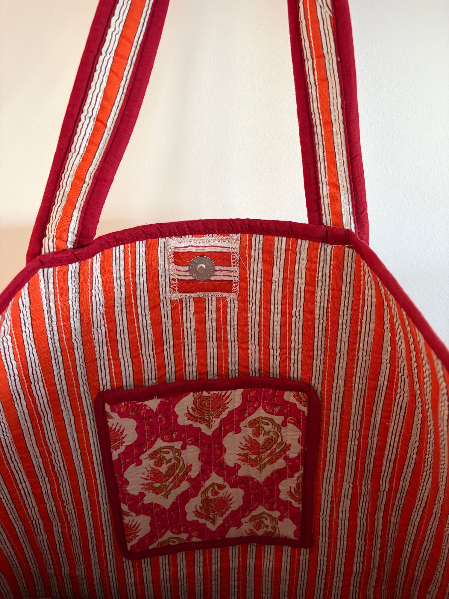 Red and white striped bag with a patterned pocket on a white background