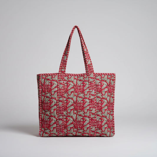 Red patterned bag on a white surface with green leaves