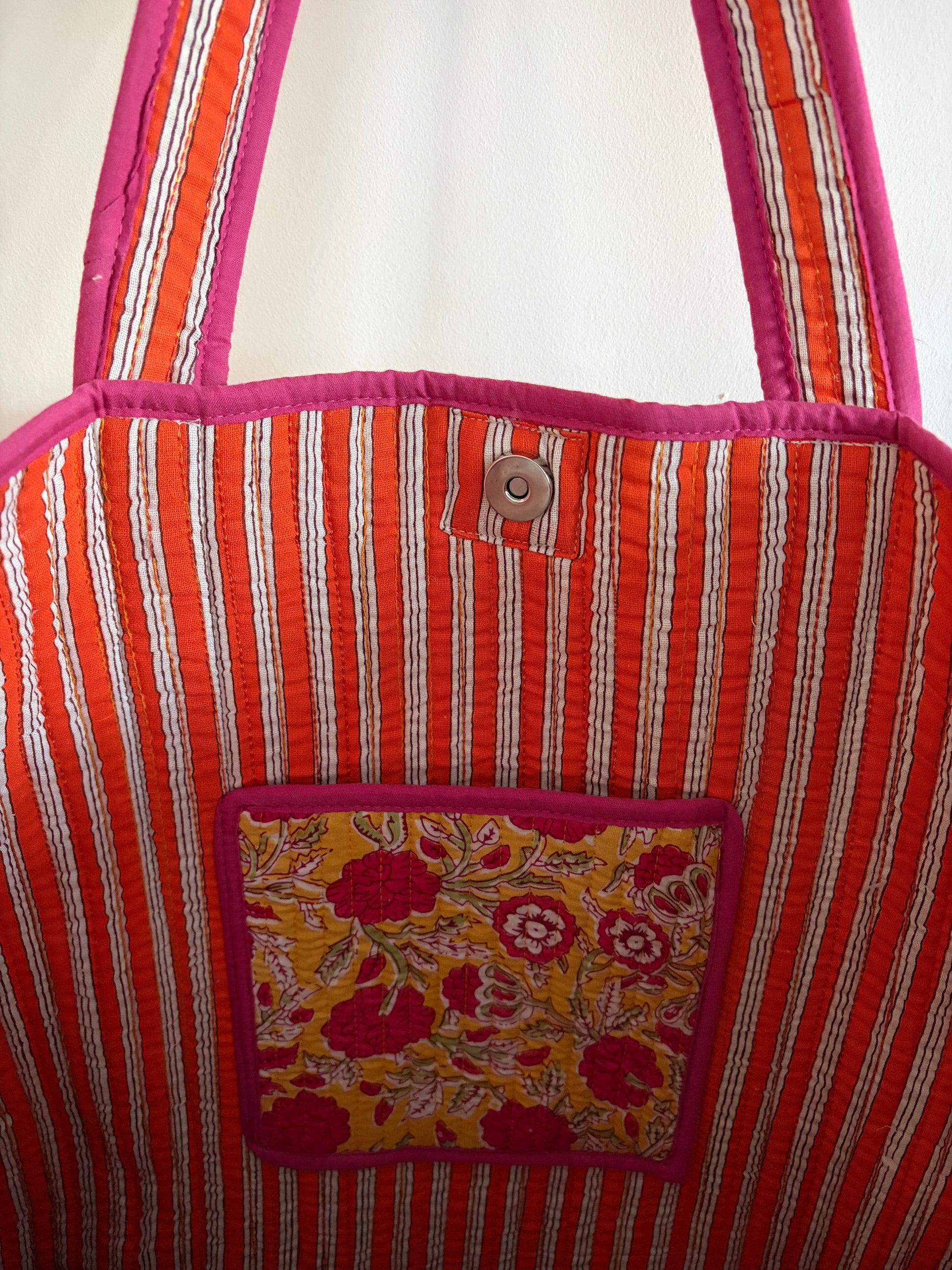 Striped fabric bag with a floral pocket on a white background