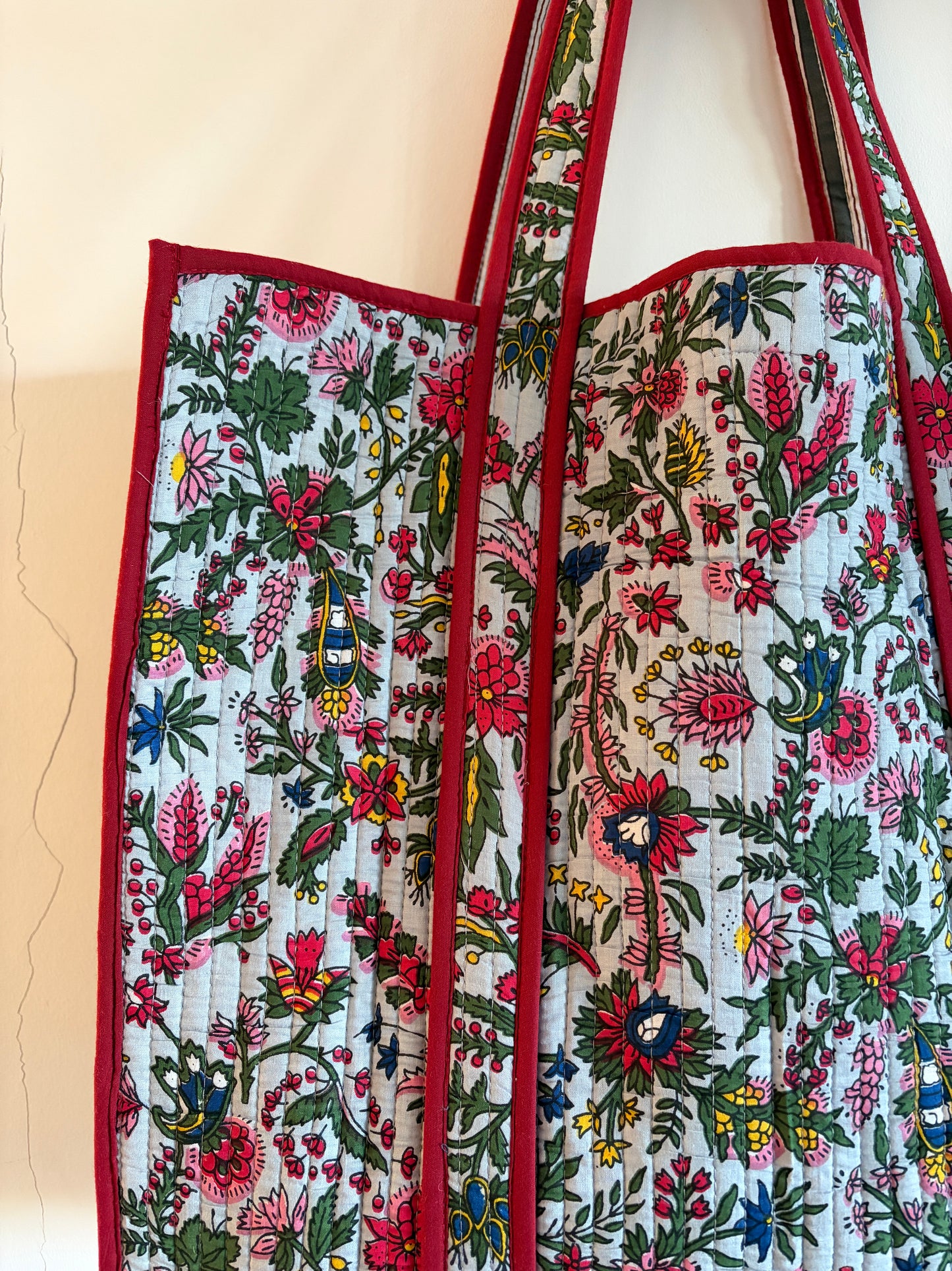 Floral patterned fabric bag with red border on a beige background