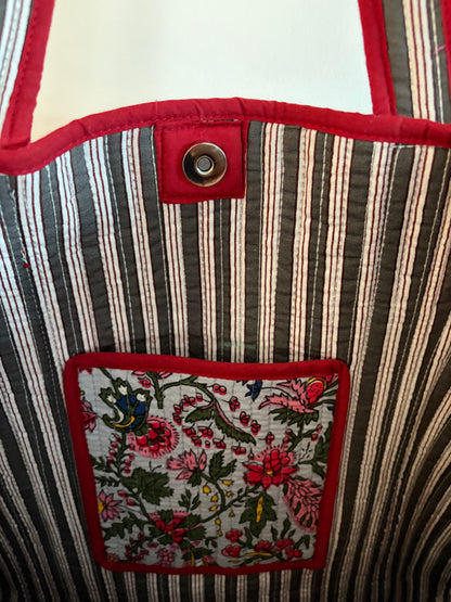Close-up of a striped fabric bag with a floral patch and button