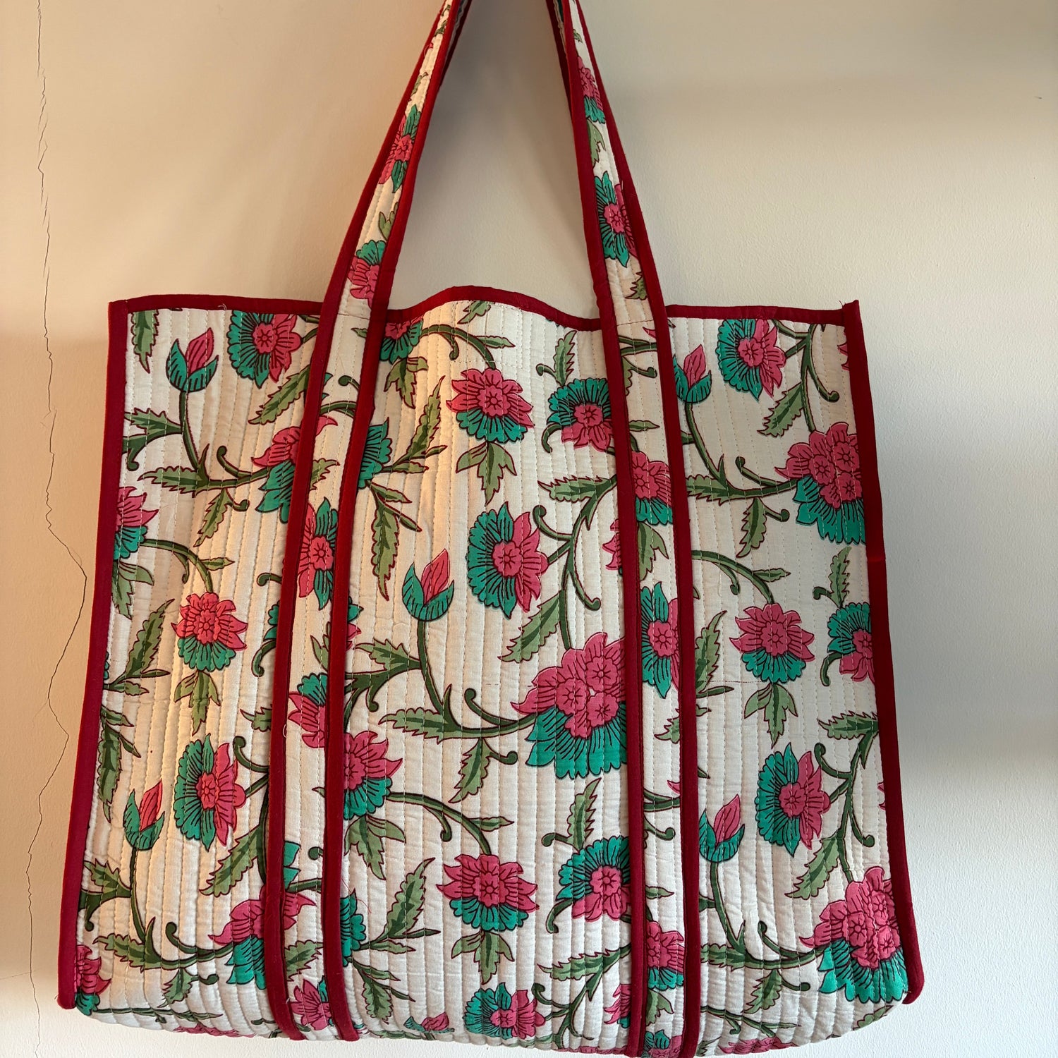 Floral-patterned bag with a red border on a beige background