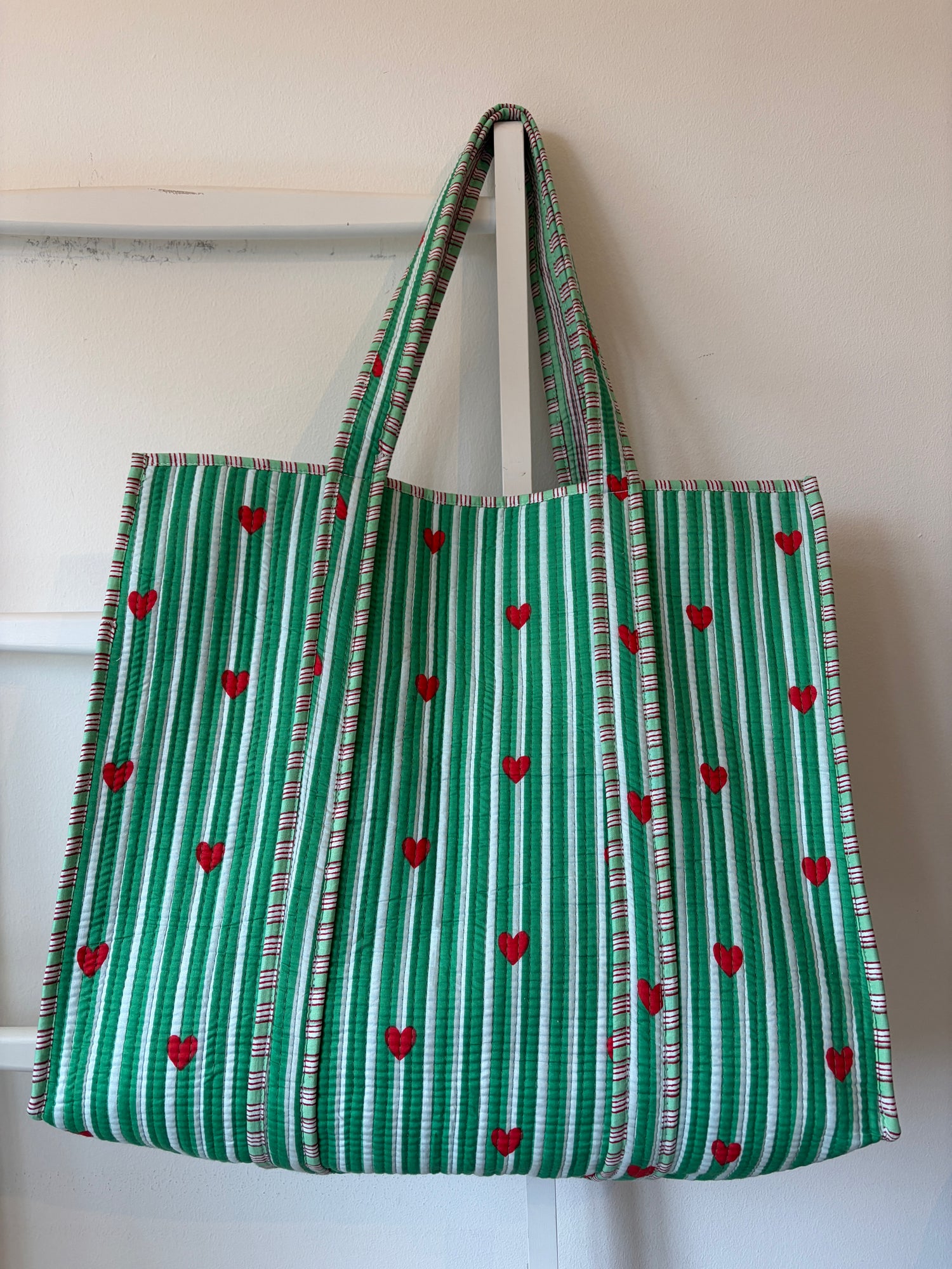 Green and white striped bag with red heart patterns on a white background