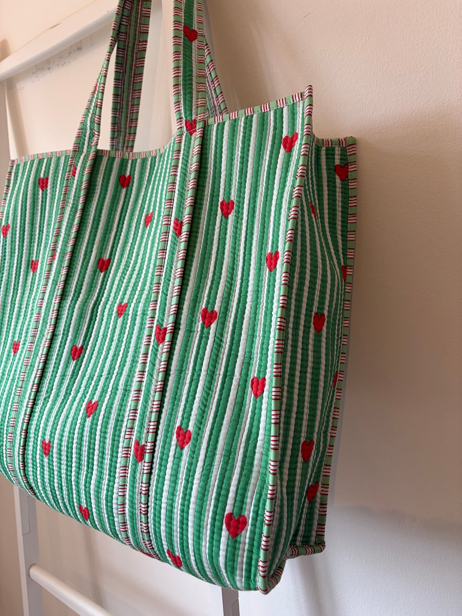 Green fabric with red heart patterns Tote bag on a white surface