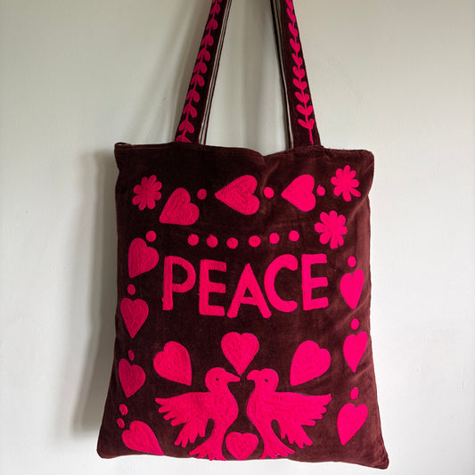 Brown tote bag with pink 'PEACE' text and heart designs on a plain background