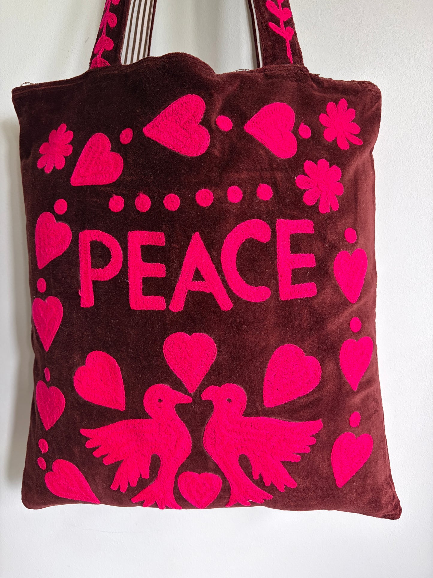 Brown tote bag with pink 'PEACE' text and heart designs on a plain background