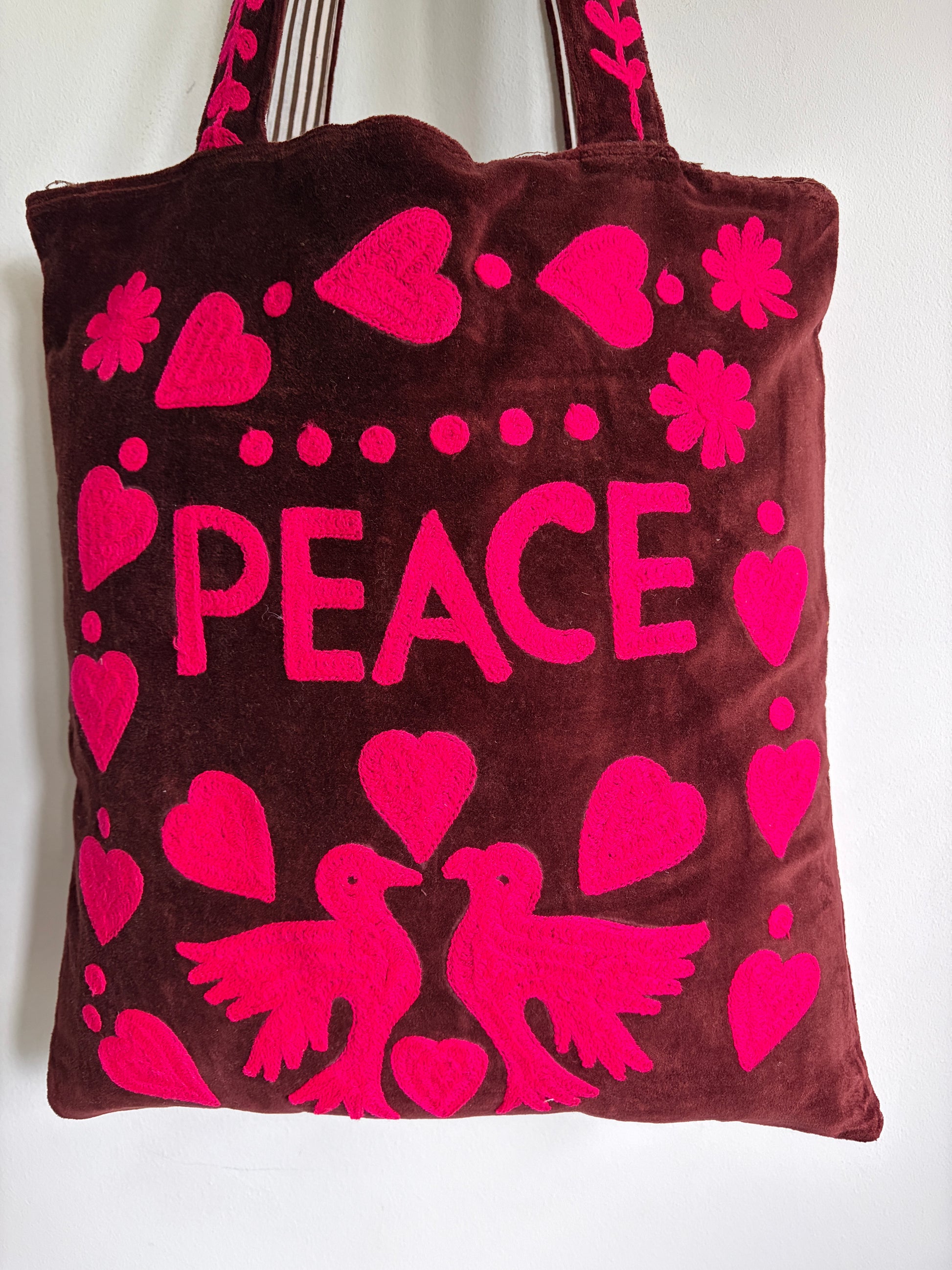 Brown tote bag with pink 'PEACE' text and heart designs on a plain background