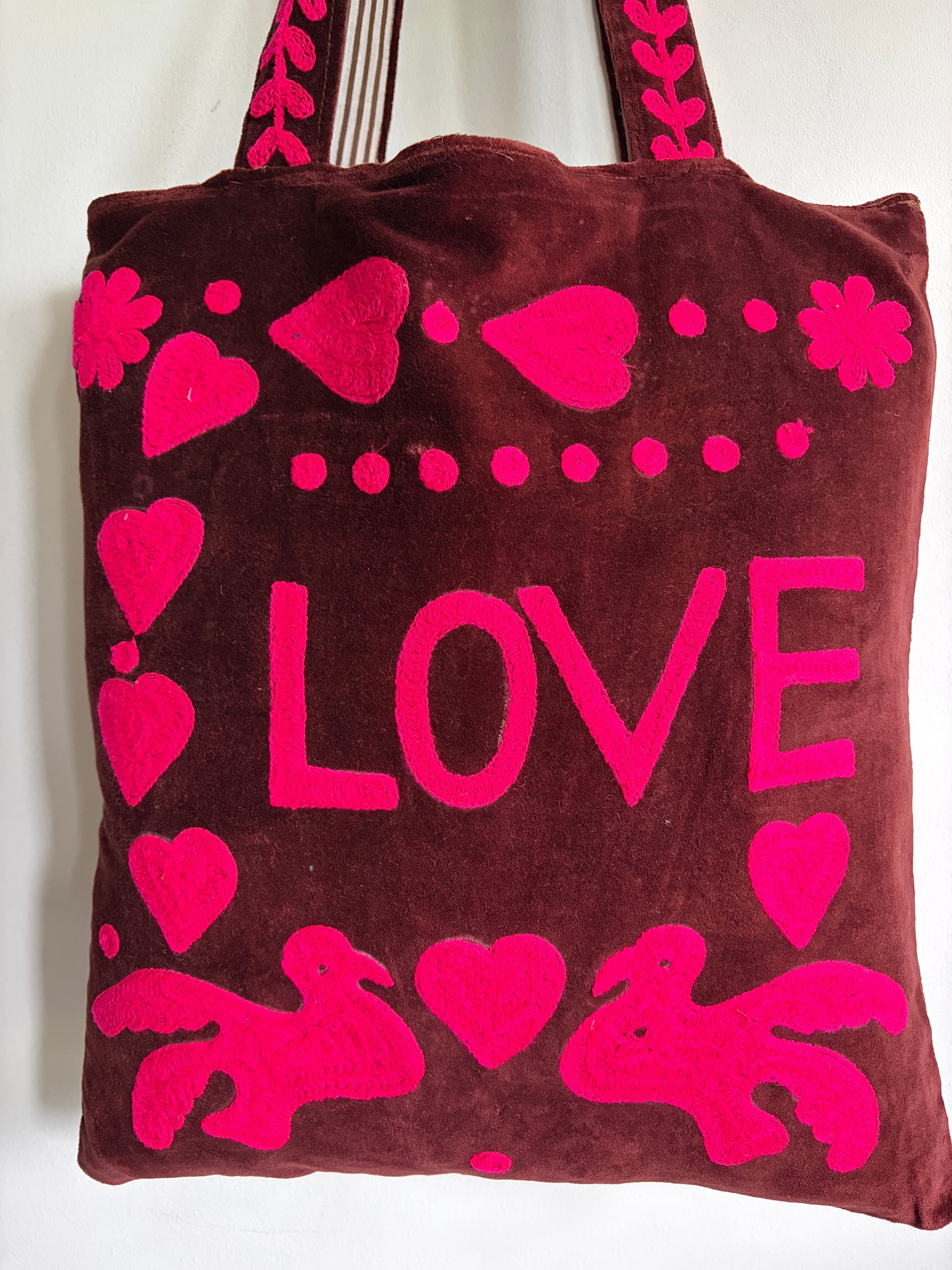 Brown tote bag with pink 'PEACE' text and heart designs on a plain background