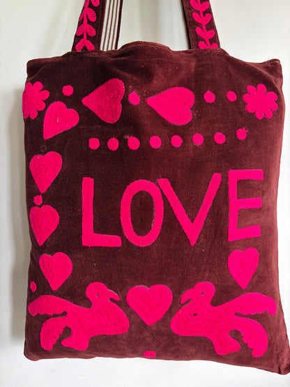 Brown tote bag with pink 'PEACE' text and heart designs on a plain background