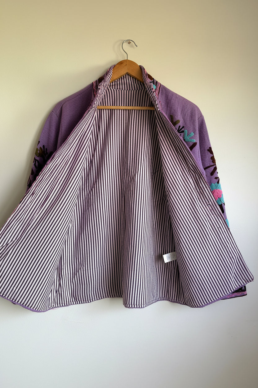Purple embroidered suzani jacket with floral patterns on a beige background