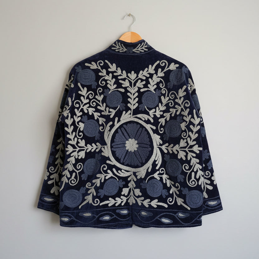 Blue embroidered suzani jacket on a hanger against a white background