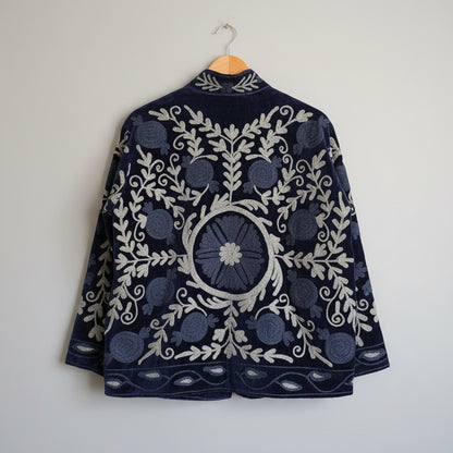Blue embroidered suzani jacket on a hanger against a white background