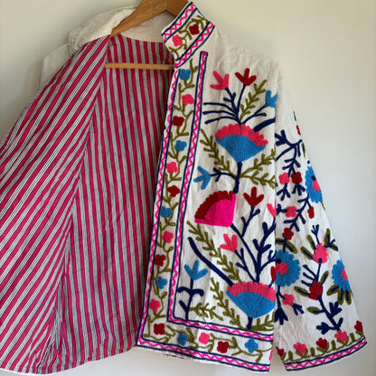 Colorful embroidered jacket on a hanger against a white background