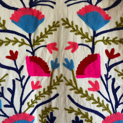 Colorful embroidered jacket on a hanger against a white background