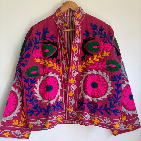 Colorful embroidered jacket on a hanger against a white background