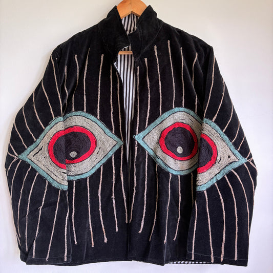 Colorful embroidered jacket on a hanger against a white background