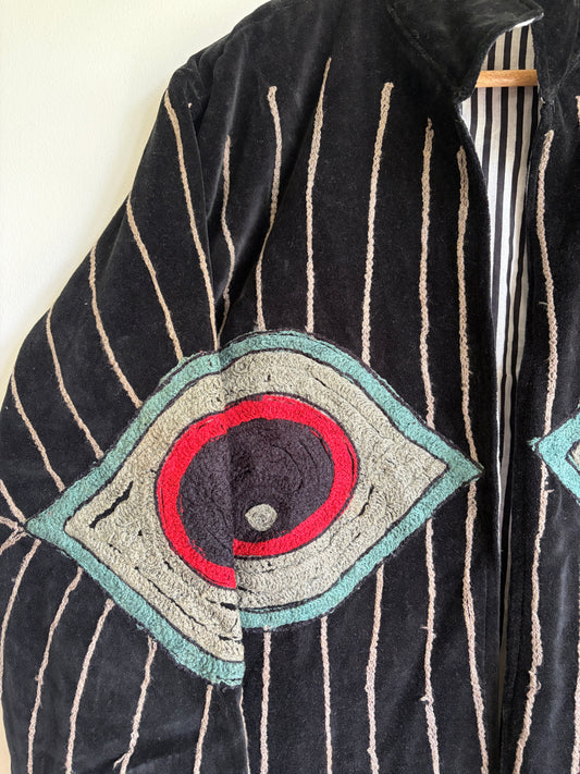 Colorful embroidered jacket on a hanger against a white background