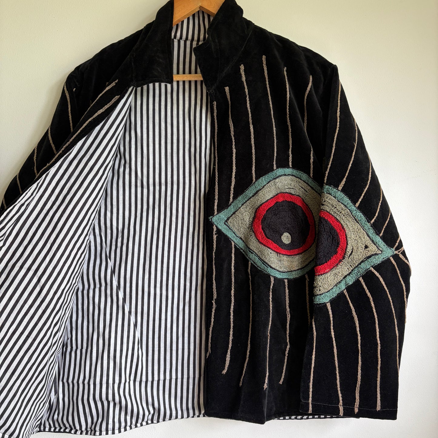 Colorful embroidered jacket on a hanger against a white background