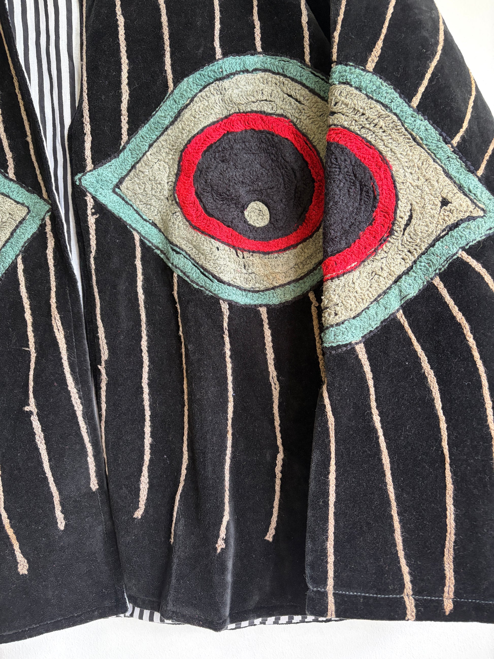 Colorful embroidered jacket on a hanger against a white background