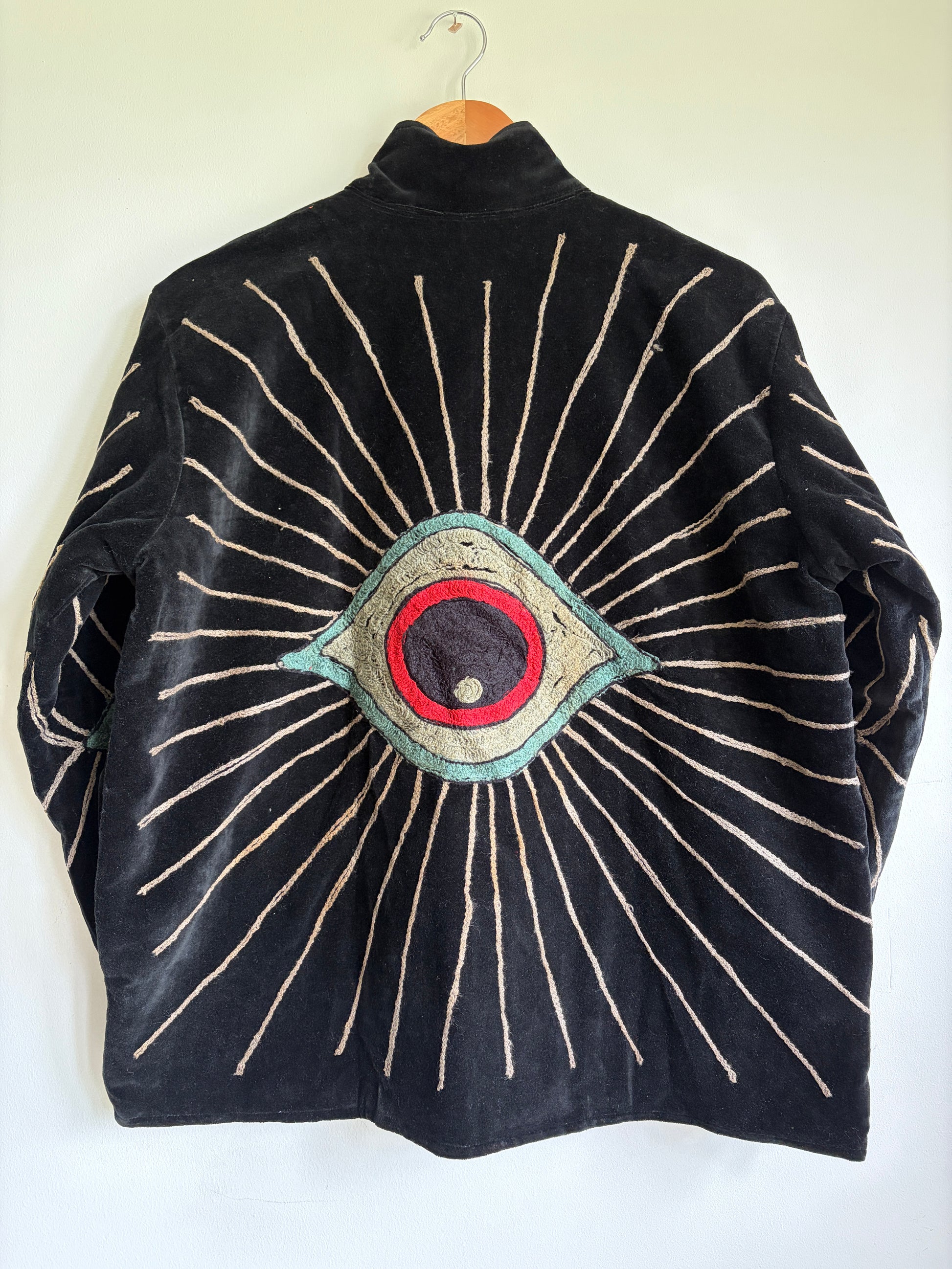Colorful embroidered jacket on a hanger against a white background