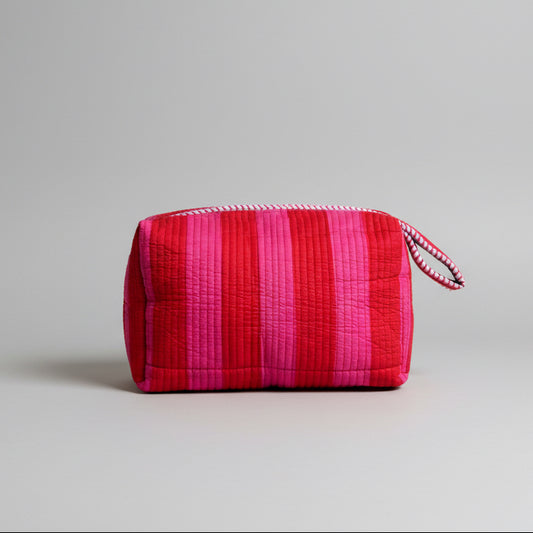 Quilted make up bag with stripes in shades of red and pink.