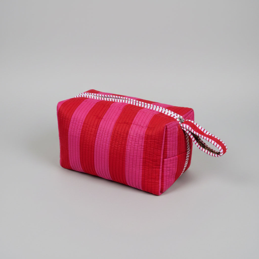 Quilted make up bag with stripes in shades of red and pink.