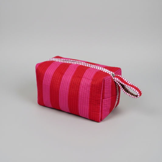 Quilted make up bag with stripes in shades of red and pink.