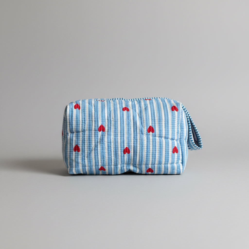 Quilted cotton make up bag with a blue and white striped pattern and red heart motifs.
