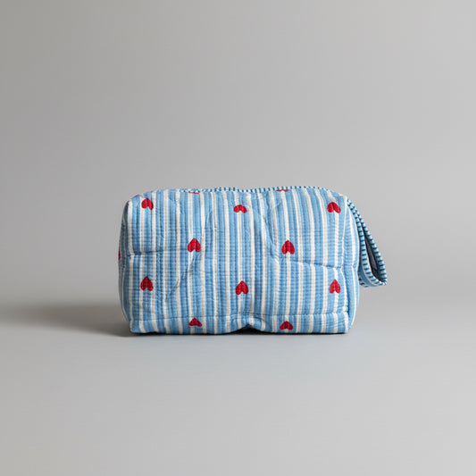 Quilted cotton make up bag with a blue and white striped pattern and red heart motifs.