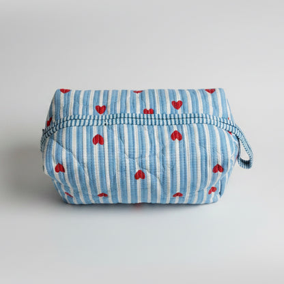 Quilted cotton make up bag with a blue and white striped pattern and red heart motifs.