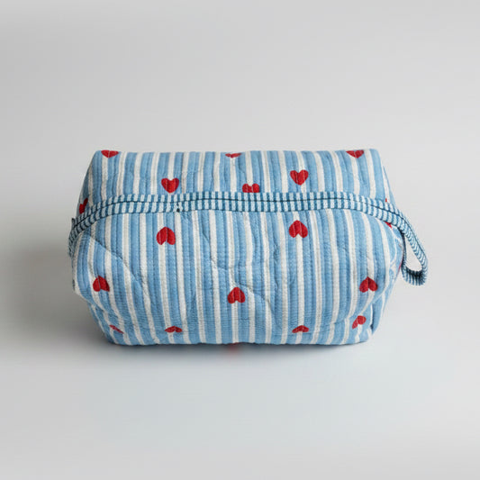 Quilted cotton make up bag with a blue and white striped pattern and red heart motifs.