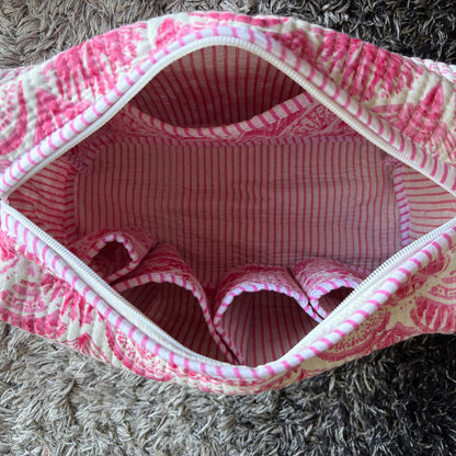 A pink and white patterned zippered make up bag with a matching loop handle.
