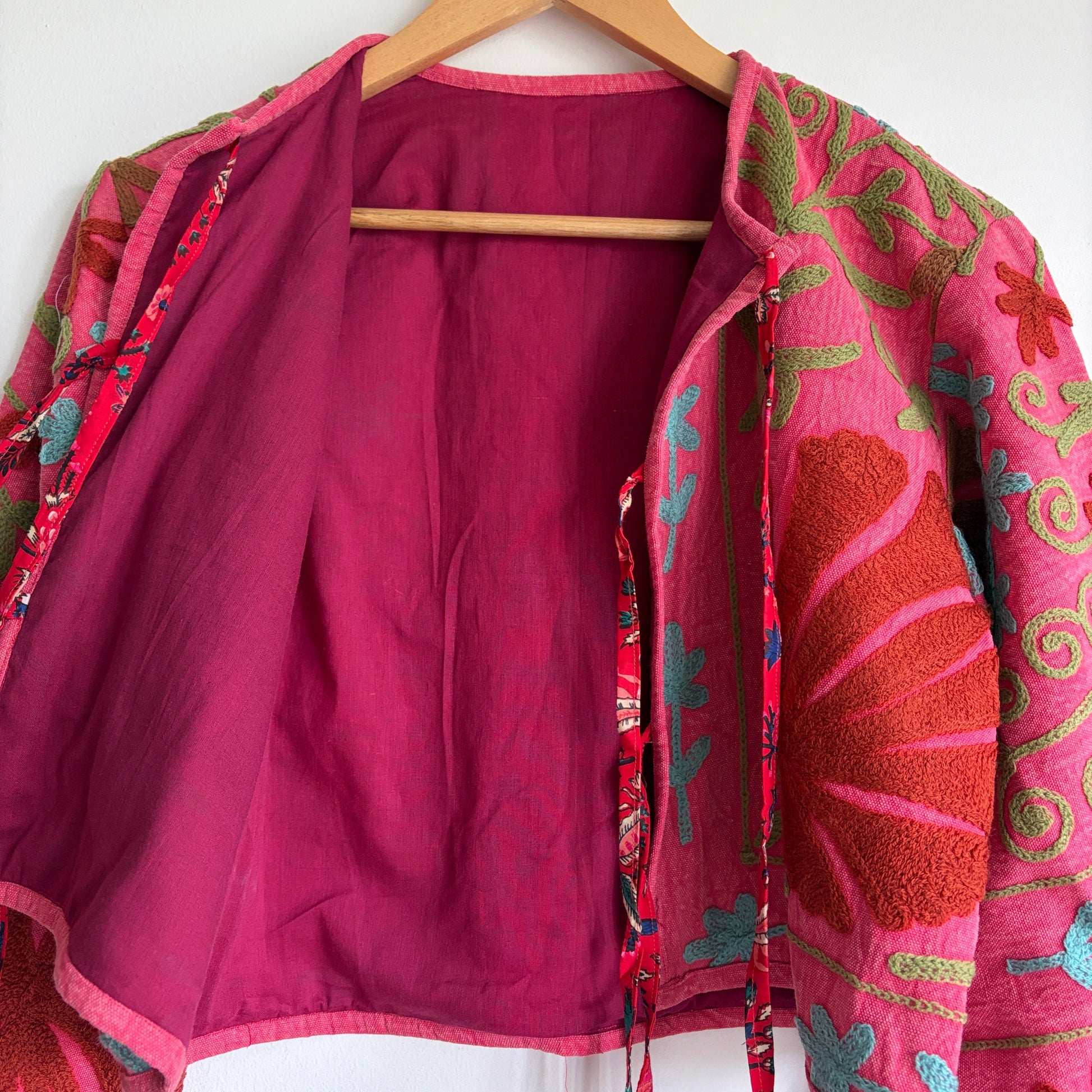 A cropped long-sleeve jacket with a vibrant pink and red floral pattern. 