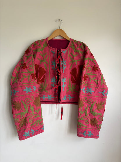 A cropped long-sleeve jacket with a vibrant pink and red floral pattern. 